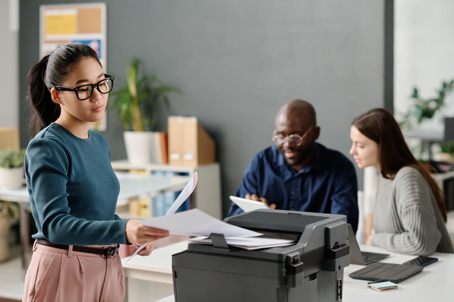 Employee using office printer in a cloud-managed print environment supporting secure and centralized workplace printing.