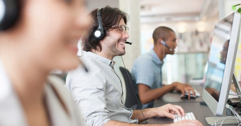 Employees wearing headsets and working at computers in a modern office, supporting a hybrid workforce through cloud-based print management and digital workflows.