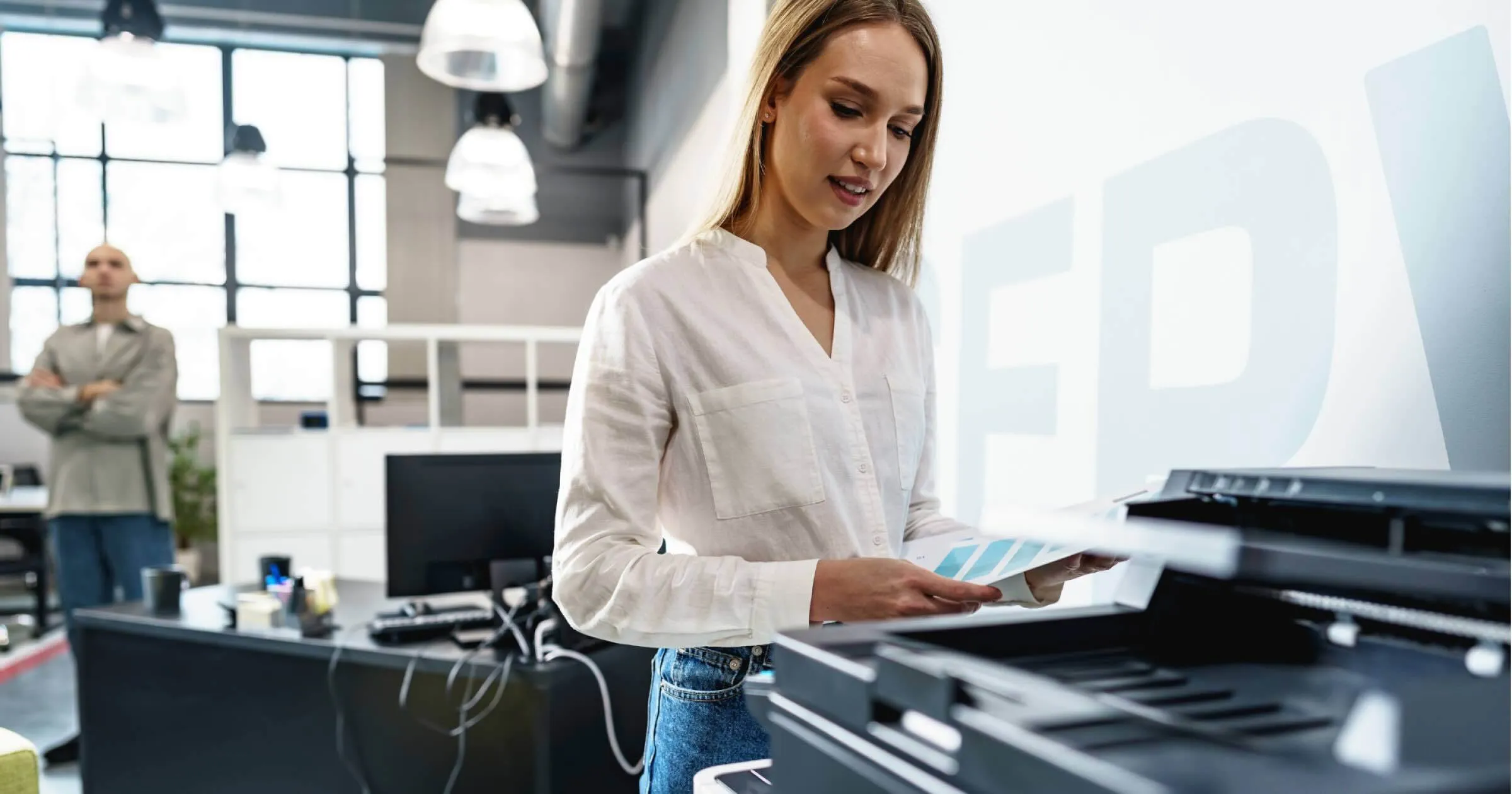 Employee collecting printed documents from an office printer as part of a modern workplace print workflow.