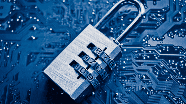 A silver combination padlock resting on a blue computer circuit board