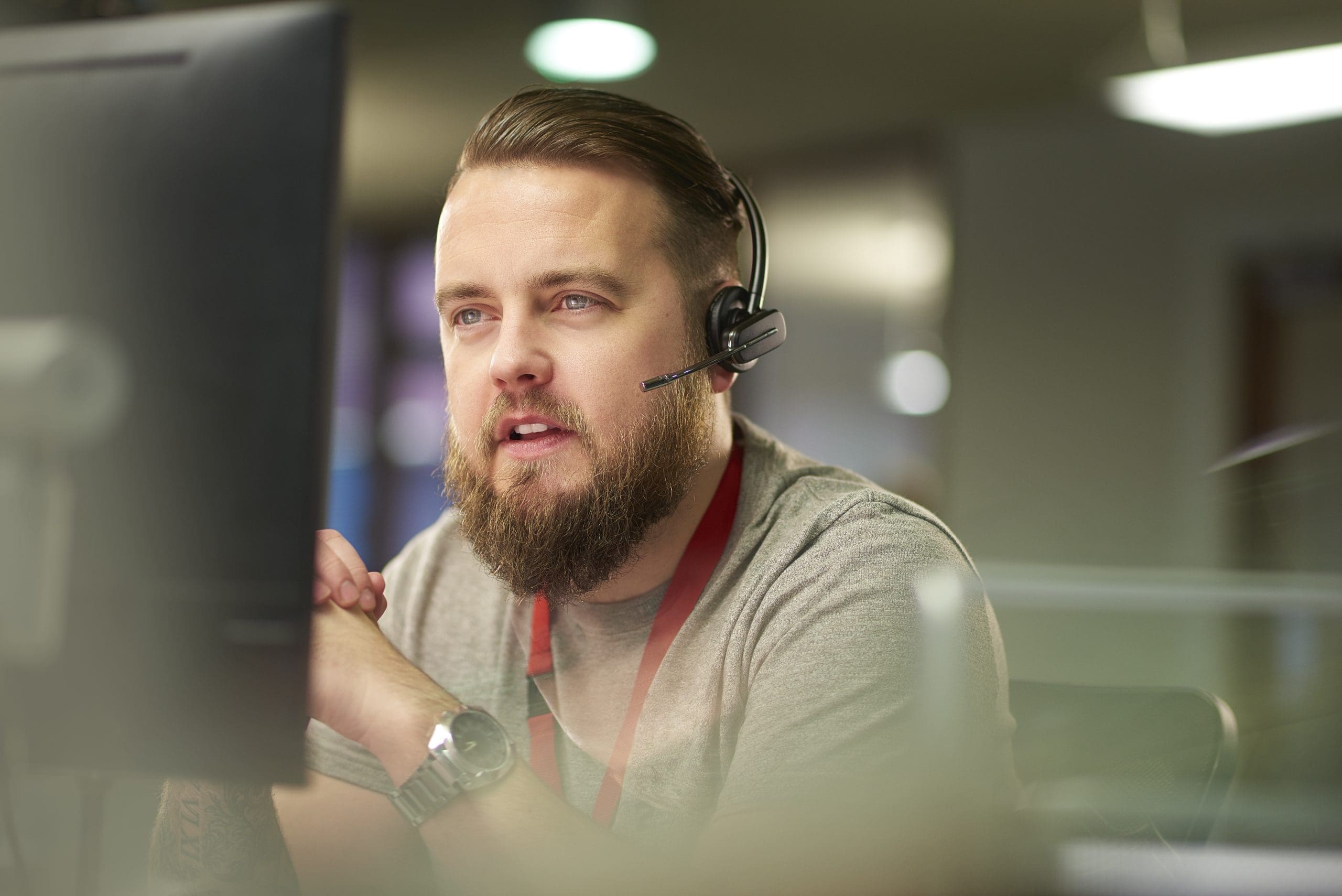 Customer support representative wearing a headset and speaking while working at a computer